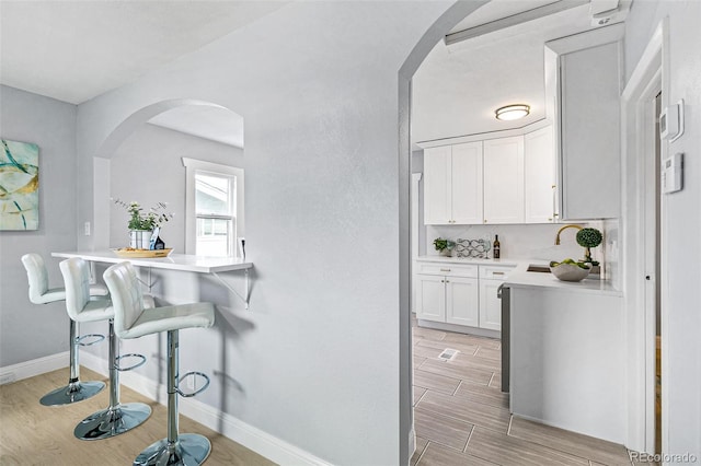 kitchen featuring white cabinetry, sink, backsplash, and a breakfast bar