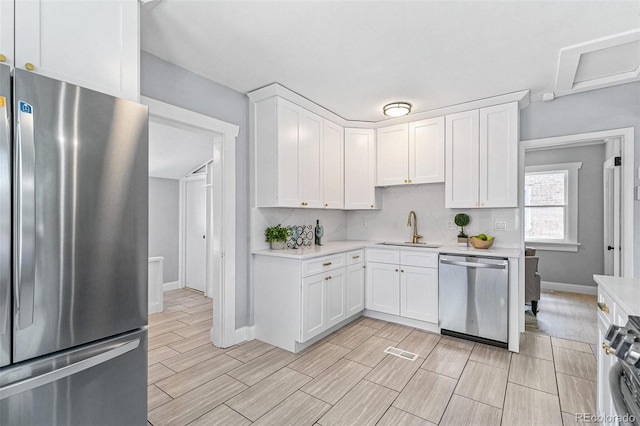 kitchen with tasteful backsplash, white cabinetry, appliances with stainless steel finishes, and sink