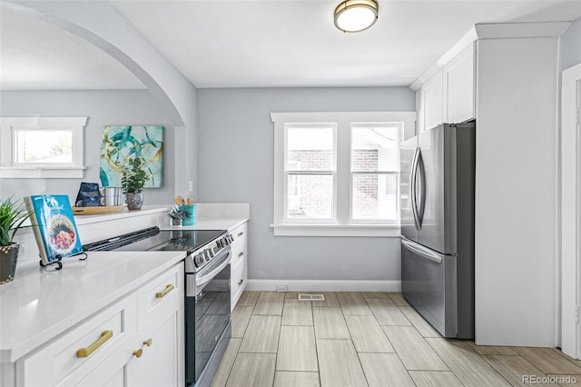 kitchen featuring stainless steel appliances, a healthy amount of sunlight, and white cabinets