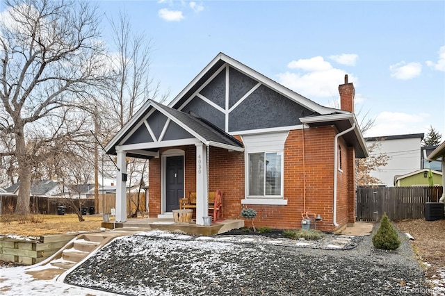 view of front of home featuring brick siding, a chimney, central AC unit, and fence