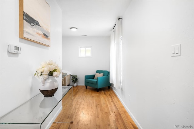 corridor with wood finished floors, visible vents, and baseboards