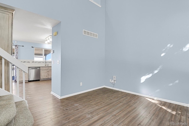 unfurnished living room with a sink, baseboards, visible vents, and wood finished floors