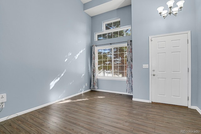 entrance foyer with an inviting chandelier, a high ceiling, baseboards, and wood finished floors