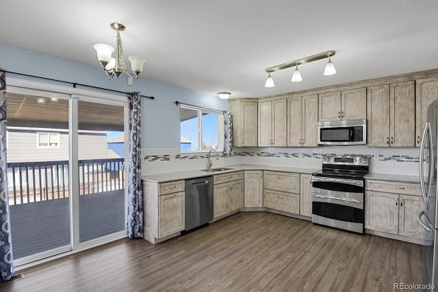 kitchen featuring stainless steel appliances, a sink, light countertops, decorative backsplash, and dark wood finished floors