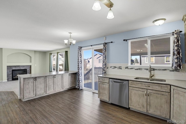 kitchen with dark wood finished floors, open floor plan, a sink, a stone fireplace, and dishwasher