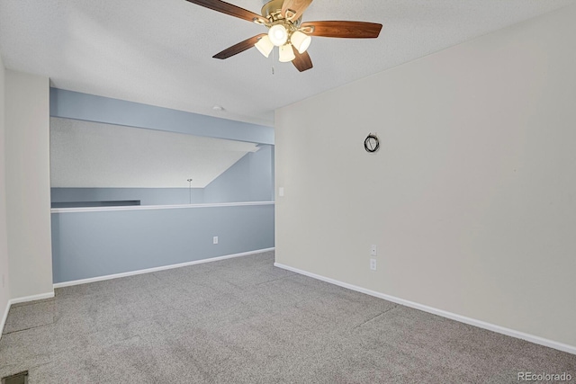 carpeted empty room with lofted ceiling, a textured ceiling, a ceiling fan, and baseboards