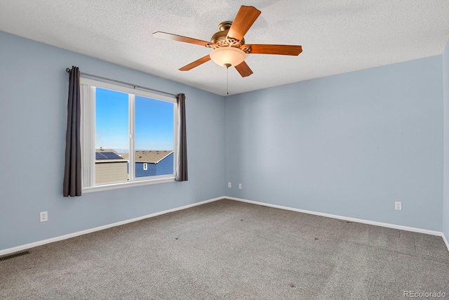 empty room with carpet, visible vents, ceiling fan, a textured ceiling, and baseboards