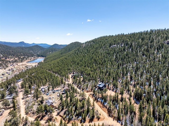 birds eye view of property featuring a water and mountain view and a wooded view