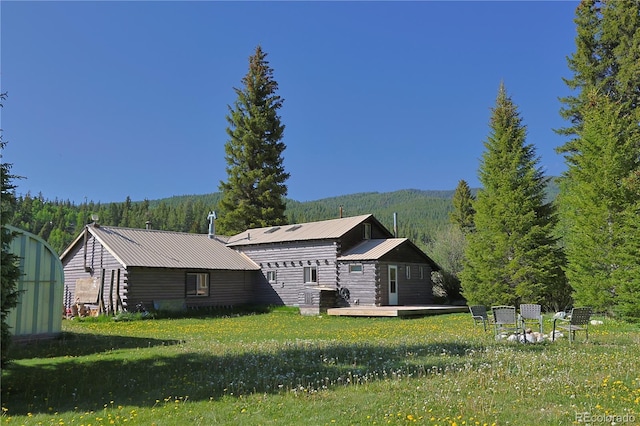 420 Quarzt Ln, Pitkin, CO 81241 - back of property featuring a deck with mountain view, a lawn, a metal roof, and a wooded view