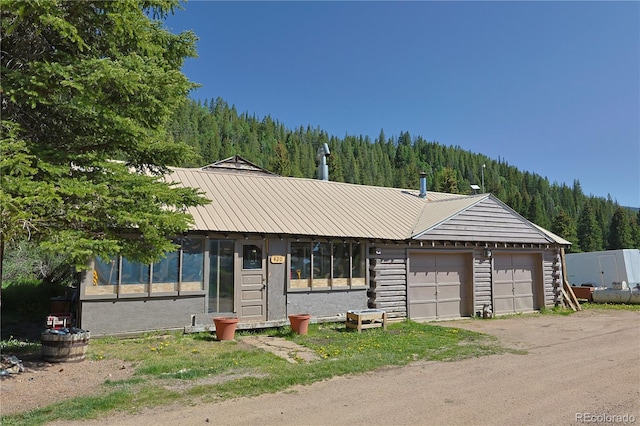 420 Quarzt Ln, Pitkin, CO 81241 - view of front of property with a forest view, a metal roof, an attached garage, and dirt driveway