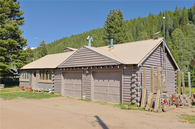 420 Quarzt Ln, Pitkin, CO 81241 - view of front of property with a garage, a forest view, a metal roof, and log exterior