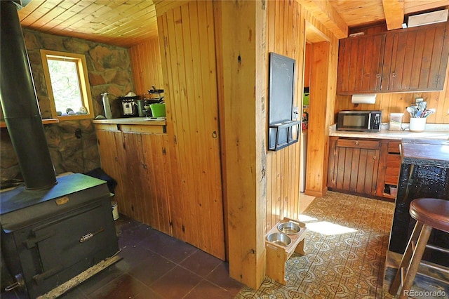 420 Quarzt Ln, Pitkin, CO 81241 - kitchen with wooden ceiling, wooden walls, a wood stove, brown cabinetry, and light countertops