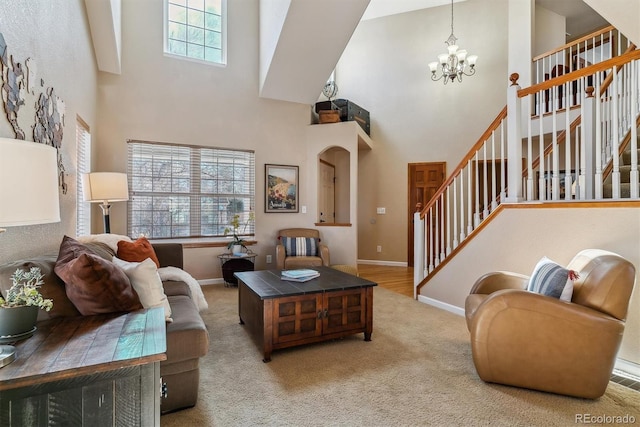 carpeted living room with a towering ceiling, stairway, baseboards, and an inviting chandelier