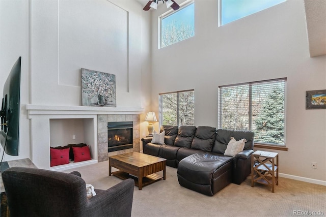 carpeted living area featuring a ceiling fan, a fireplace, plenty of natural light, and baseboards