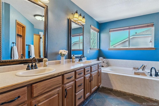 full bathroom featuring a textured wall, double vanity, a sink, and a bath