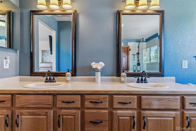 full bath with double vanity, a stall shower, a sink, and a textured wall