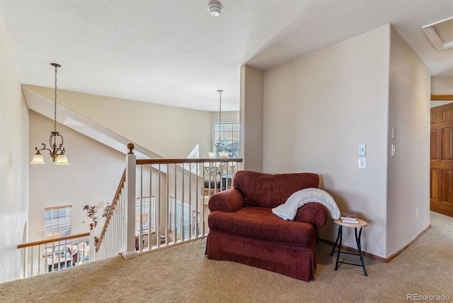 sitting room featuring a textured ceiling, carpet, an upstairs landing, and a notable chandelier