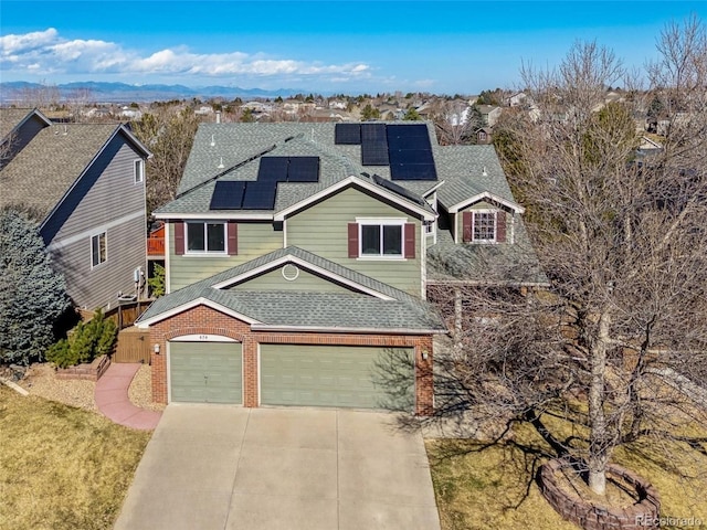 view of front of property with roof mounted solar panels, roof with shingles, driveway, and brick siding