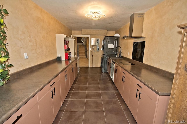 kitchen featuring kitchen peninsula, stacked washer / drying machine, ventilation hood, water heater, and dark tile patterned flooring