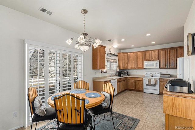 kitchen with white appliances, sink, pendant lighting, an inviting chandelier, and light tile patterned flooring