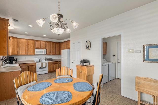 dining area featuring sink, light tile patterned floors, washer and dryer, and an inviting chandelier