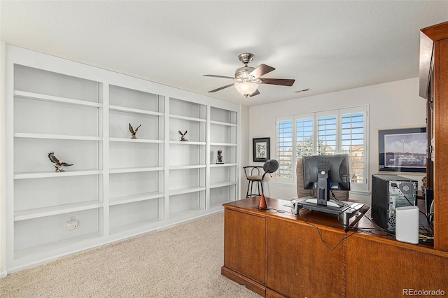 carpeted office with a textured ceiling and ceiling fan