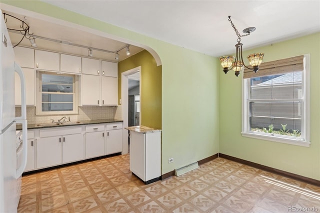1832 S Saint Paul St, Denver, CO 80210 - kitchen featuring arched walkways, freestanding refrigerator, white cabinetry, a chandelier, and rail lighting