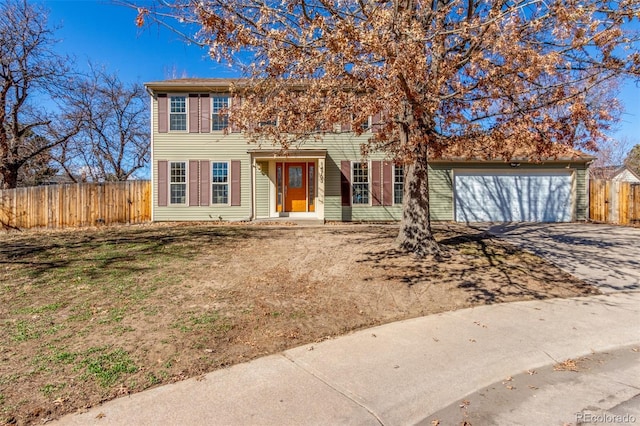 colonial inspired home with a garage, concrete driveway, a front lawn, and fence