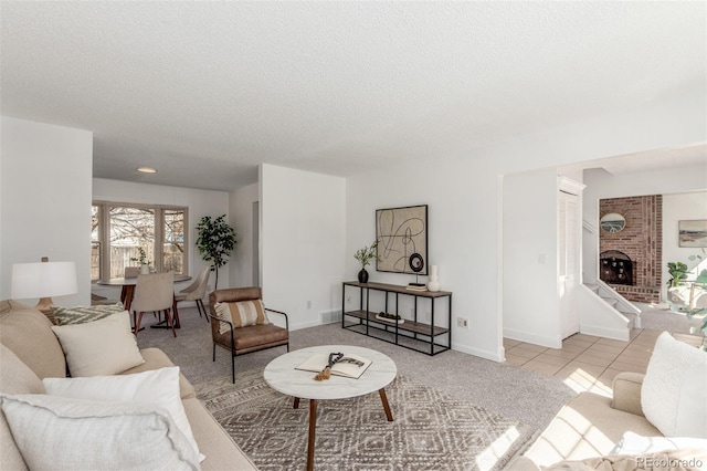 living area featuring light tile patterned floors, a fireplace, baseboards, and a textured ceiling