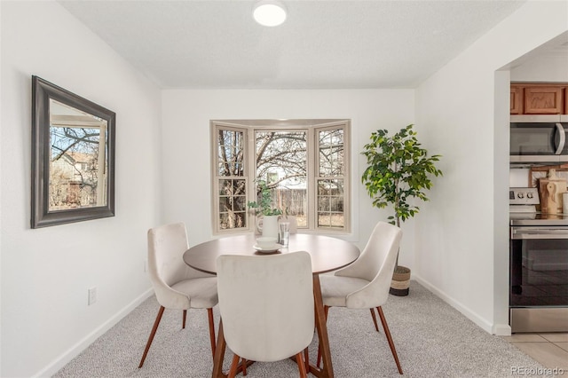 dining space featuring light colored carpet and baseboards