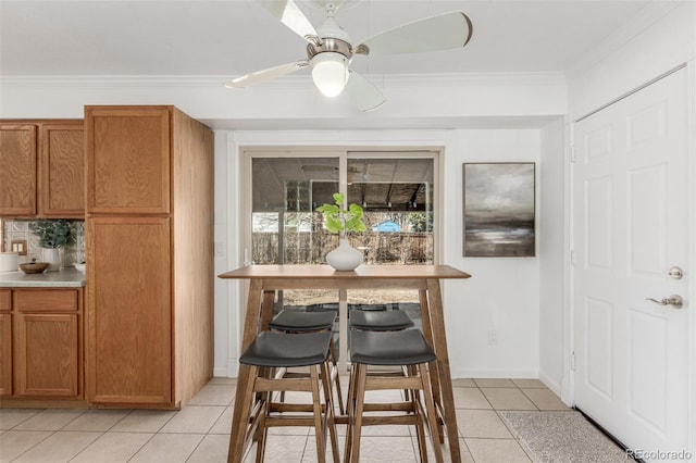 interior space featuring ceiling fan, light tile patterned flooring, baseboards, and crown molding