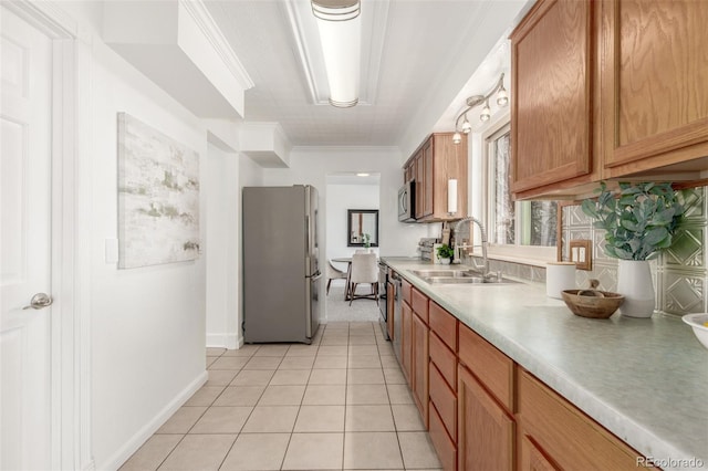 kitchen with light tile patterned floors, stainless steel appliances, light countertops, brown cabinetry, and a sink