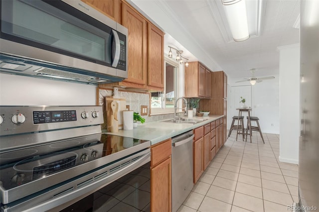 kitchen featuring brown cabinets, light tile patterned floors, stainless steel appliances, and light countertops