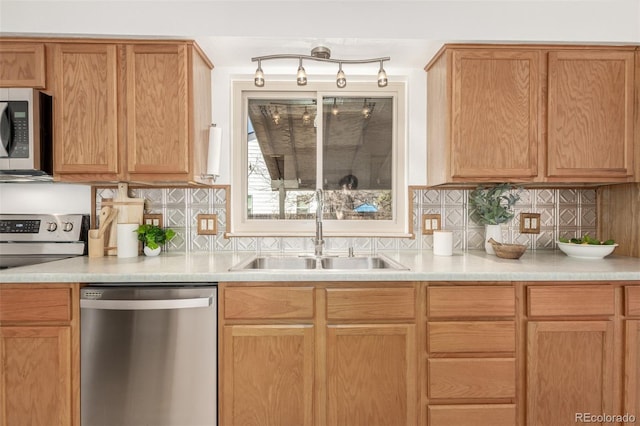 kitchen with light countertops, appliances with stainless steel finishes, a sink, and decorative backsplash