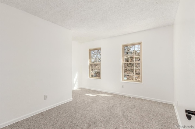 unfurnished room with visible vents, a textured ceiling, baseboards, and carpet flooring