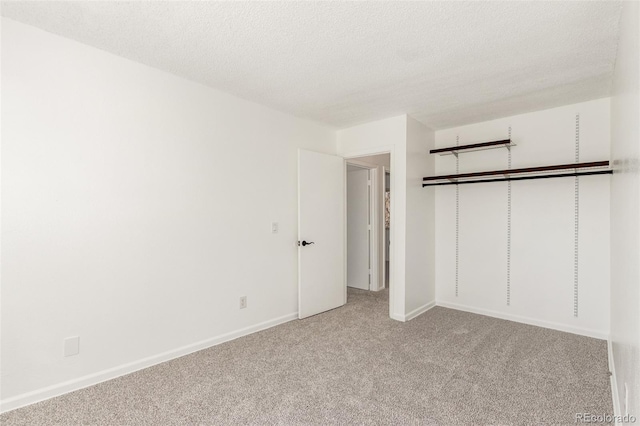 unfurnished bedroom with a closet, light carpet, a textured ceiling, and baseboards