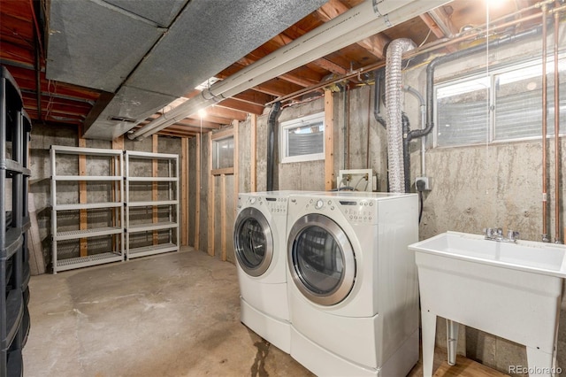 clothes washing area with laundry area, a sink, and washer and dryer