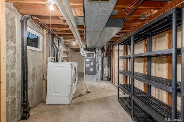 unfinished basement with water heater, washer and clothes dryer, visible vents, and heating unit