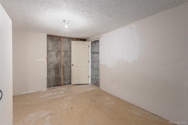 spare room featuring a textured ceiling and unfinished concrete flooring