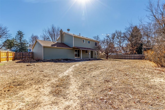 back of property featuring a chimney and a fenced backyard