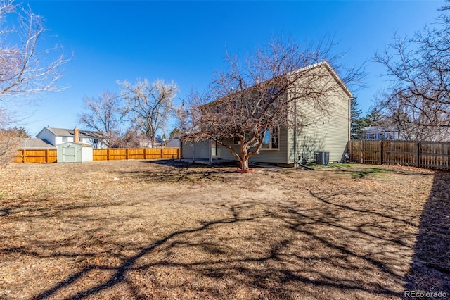 rear view of house with an outbuilding, a fenced backyard, central AC, and a storage unit