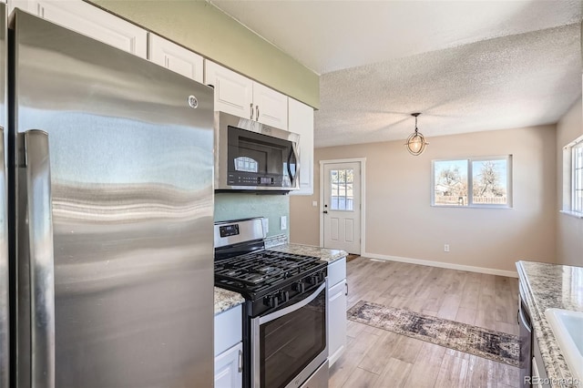 490 Washington Ave Unit A & B, Bennett, CO 80102 - kitchen featuring stainless steel appliances, white cabinets, a textured ceiling, light wood-type flooring, and light stone countertops