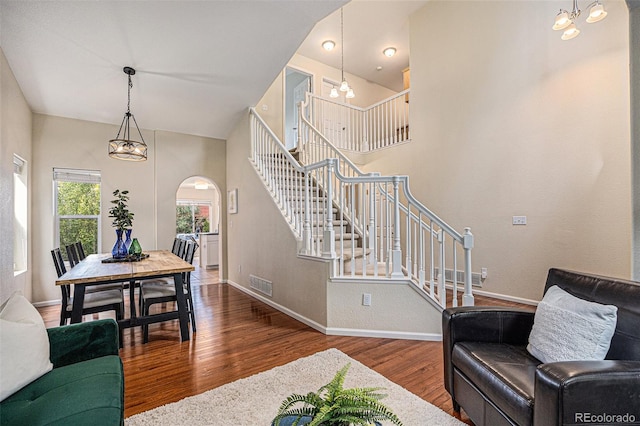 3289 Cummings Dr, Erie, CO 80516 - living area with arched walkways, wood finished floors, stairs, a chandelier, and a high ceiling