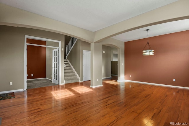 spare room featuring wood-type flooring and a notable chandelier