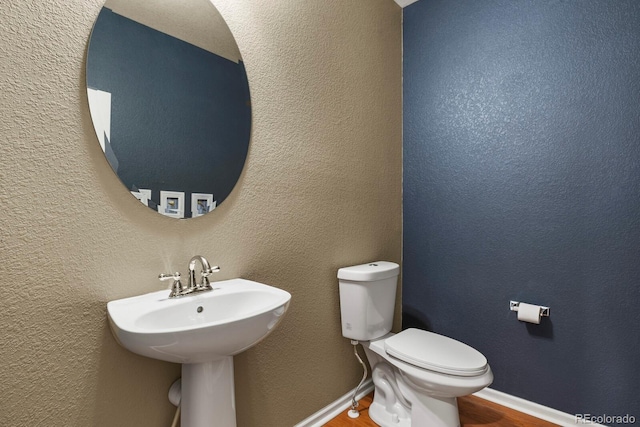 bathroom with hardwood / wood-style flooring, toilet, and sink