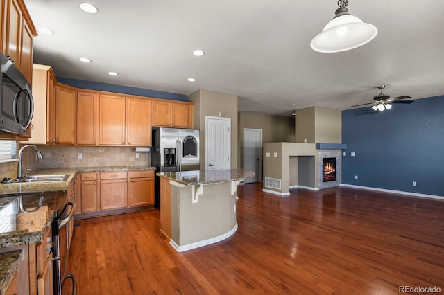 kitchen featuring sink, stainless steel appliances, decorative light fixtures, decorative backsplash, and a kitchen island