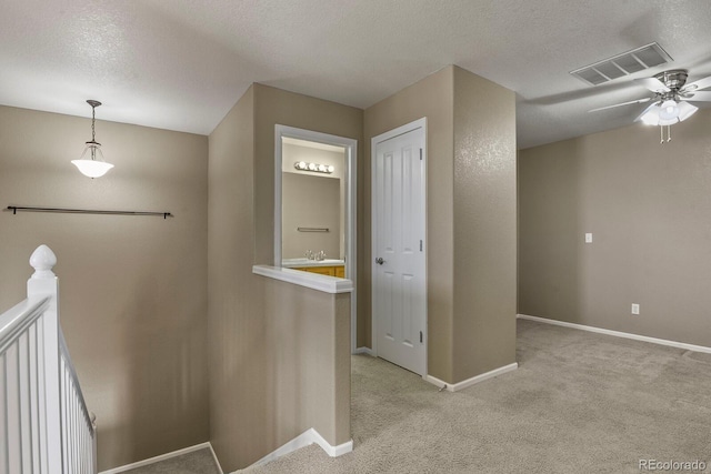 corridor with a textured ceiling and light carpet