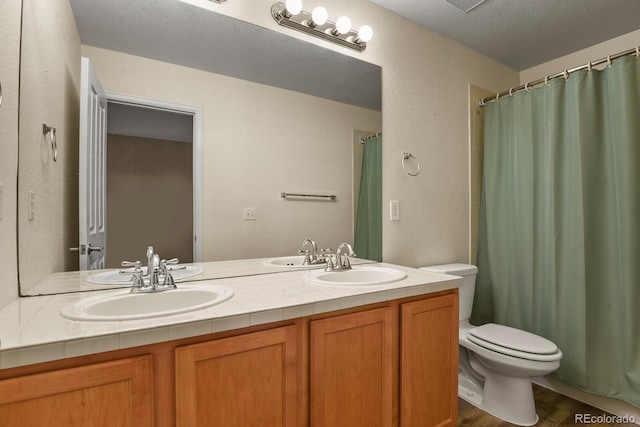 bathroom featuring hardwood / wood-style floors, vanity, toilet, and a textured ceiling