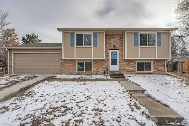 raised ranch with a garage, brick siding, and stucco siding