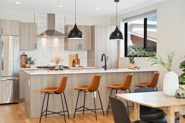 kitchen featuring wall chimney range hood, stainless steel appliances, modern cabinets, and light countertops